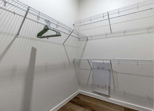 A white closet with a hanger and a white cabinet.