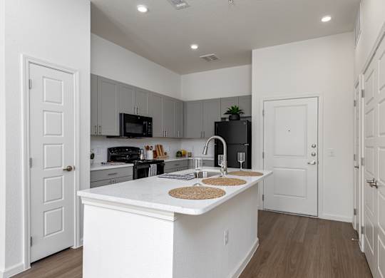 A kitchen with white cabinets and a white island with a sink.