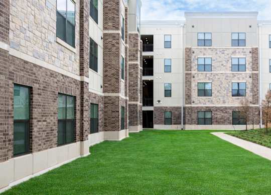 A grassy courtyard is surrounded by a brick building.