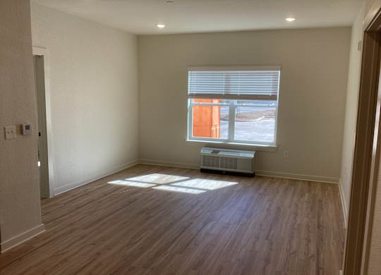 A room with wooden floors and a window with blinds.