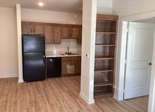 A kitchen with a black fridge and wooden cabinets.
