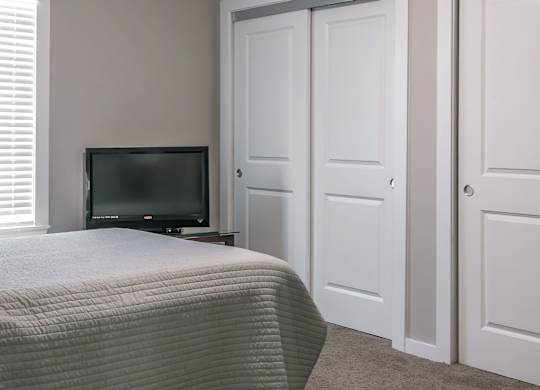 A bedroom with a bed, television, and two doors.