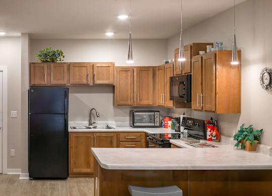 A kitchen with wooden cabinets and a black refrigerator.