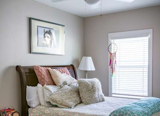 A bedroom with a bed, nightstand, and a ceiling fan.