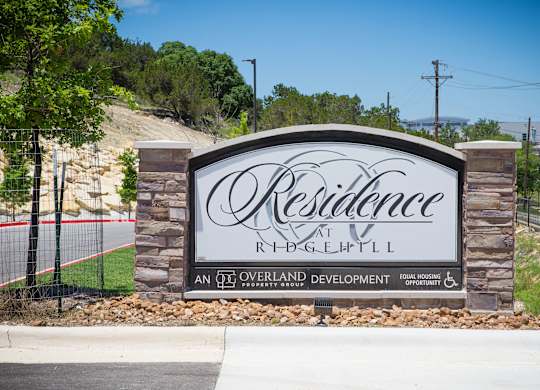 A sign for Resilience at Ridgepoint, an overland development, is displayed in front of a hill.