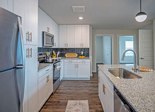 A kitchen with white cabinets and a granite countertop.