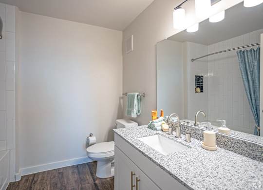 A bathroom with a white toilet, sink, and mirror.