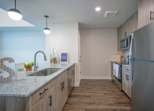 A kitchen with a refrigerator, sink, and cabinets.