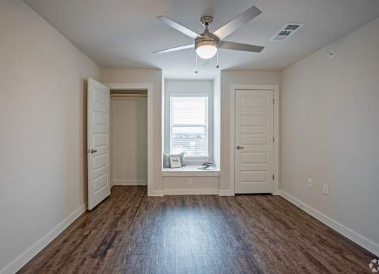 A room with a ceiling fan and a window with blinds.