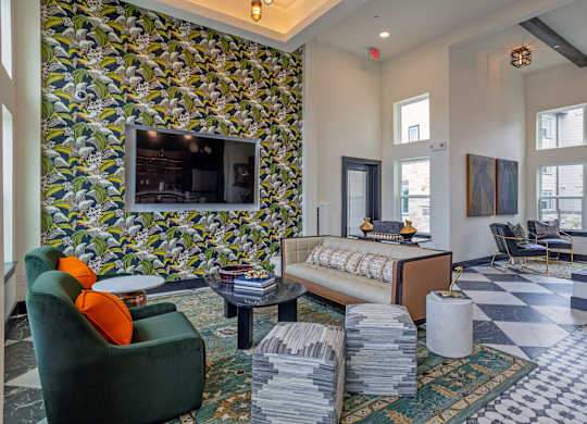 A living room with a green armchair and a patterned wallpaper.