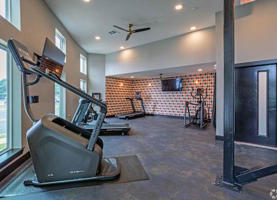 A treadmill is in a room with a ceiling fan and a window.