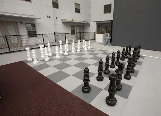 A giant chess set is set up on a checkered floor.