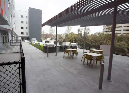 A patio with tables and chairs is covered by a roof.