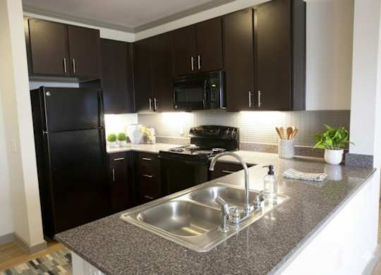A kitchen with black cabinets and a granite countertop.