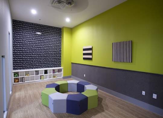 A room with a green wall and a black and white striped picture on the wall.