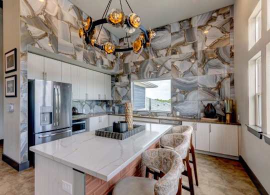 A kitchen with a marble backsplash and a large island.