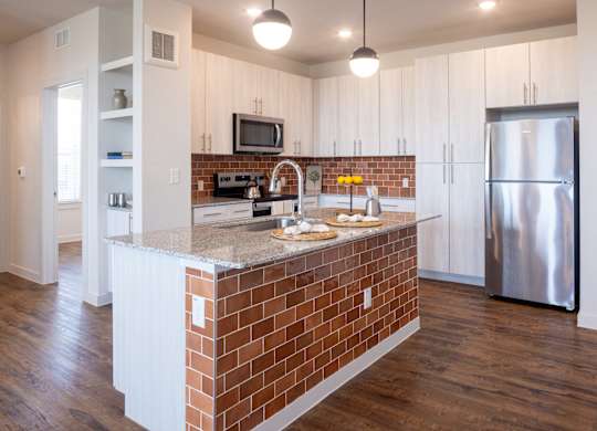 A kitchen with a brick island and stainless steel appliances.