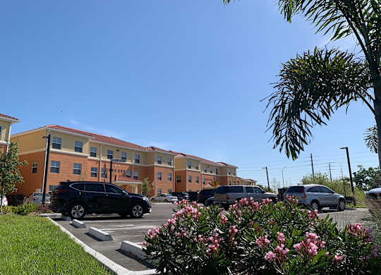 A black car is parked in a parking lot in front of a building.