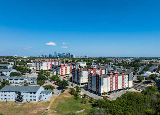 A view of a residential area with apartment buildings and a city skyline in the distance.