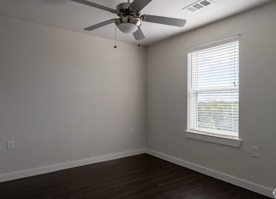 A room with a ceiling fan and a window with blinds.