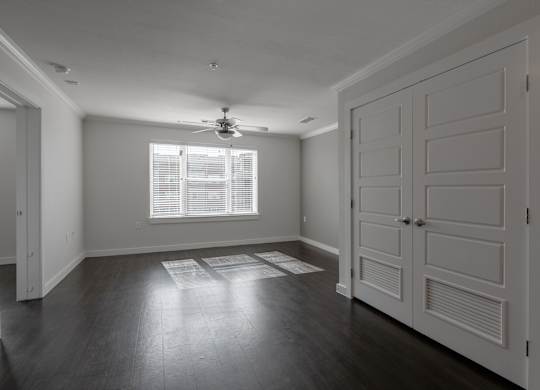 A room with a ceiling fan and a window with blinds.