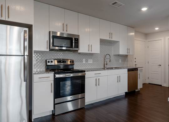 A modern kitchen with white cabinets and stainless steel appliances.