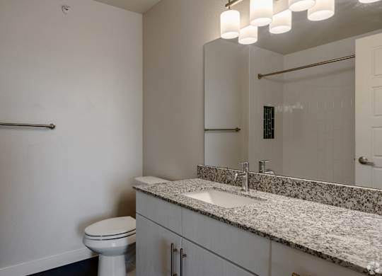 A bathroom with a toilet, sink, and mirror.