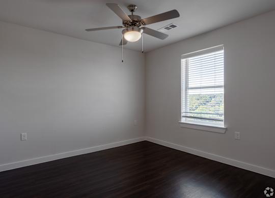 A room with a ceiling fan and a window with blinds.