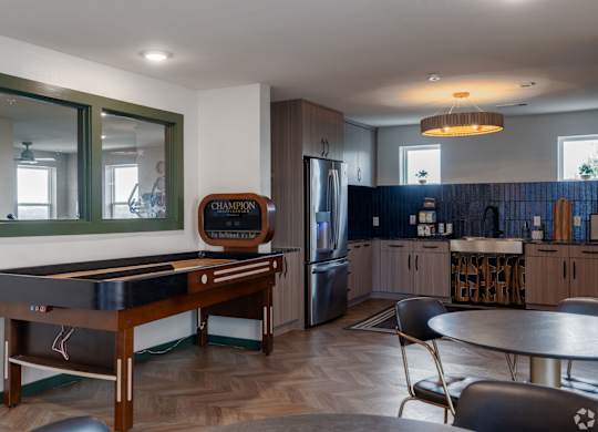 A pool table in a room with a fridge and a bar.