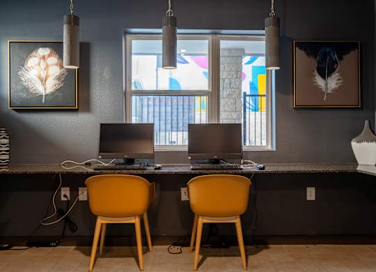 Two chairs are placed in front of a desk with two computers.