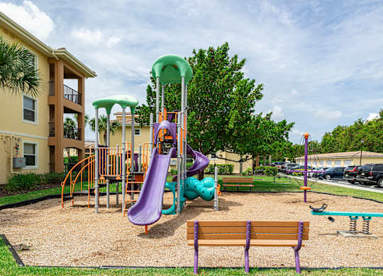 A playground with a purple slide and a green canopy.