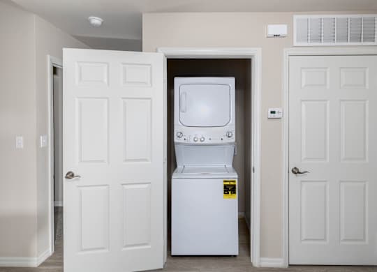 A white fridge is in a room with two white doors.
