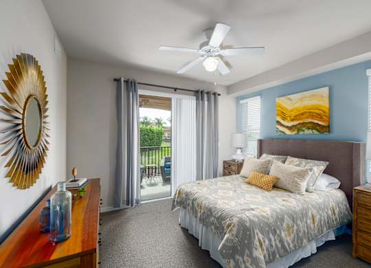 A bedroom with a bed, dresser, mirror, and a ceiling fan.