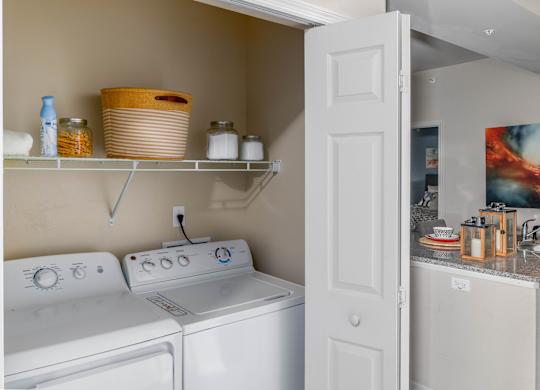 A laundry room with a washer and dryer and a shelf above them.