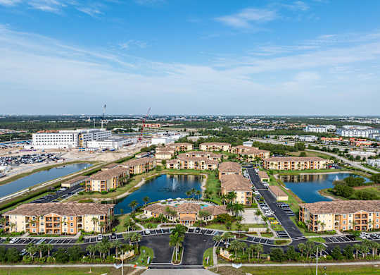 A large, well-maintained residential complex with a lake and a parking lot.