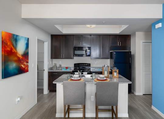 A modern kitchen with a dining table set for two.