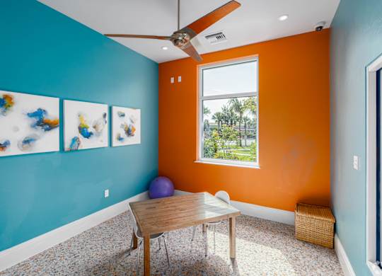 A room with a table, chairs, and a ceiling fan.