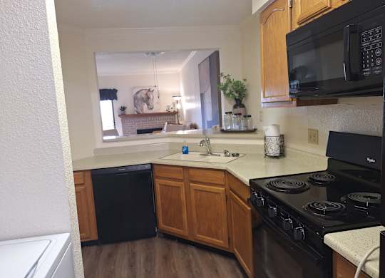 A kitchen with a black stove top oven and wooden cabinets.