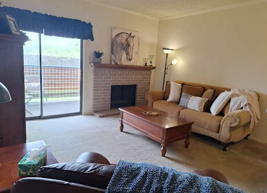 A living room with a fireplace and a painting of a horse on the wall.