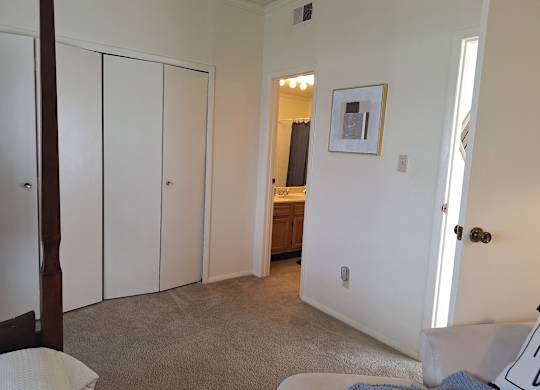 A bedroom with a white bed and a picture on the wall.