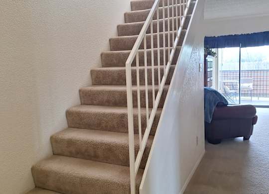A staircase with beige carpeted steps and white railings.