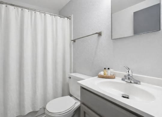 A white bathroom with a toilet, sink, and shower curtain.