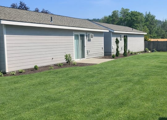 A house with a grey roof and a green lawn in front.