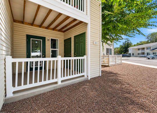 A white house with a brown roof and a green door.