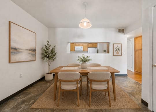 A dining room with a table set for two and a painting on the wall.