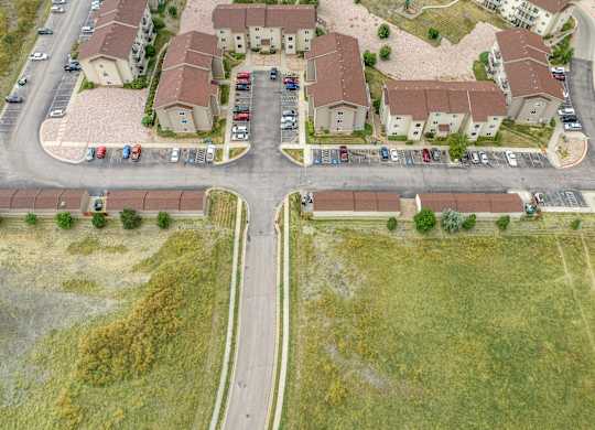 A road with cars parked on the side and houses in the background.