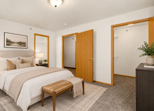 A bedroom with a bed, a bench, and a painting on the wall.