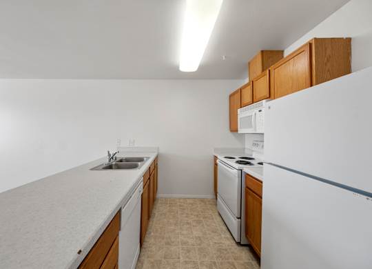 A kitchen with white appliances and wooden cabinets.
