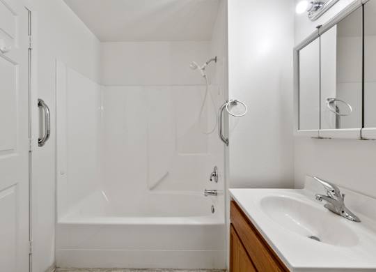 A white bathroom with a tub, sink, and mirror.