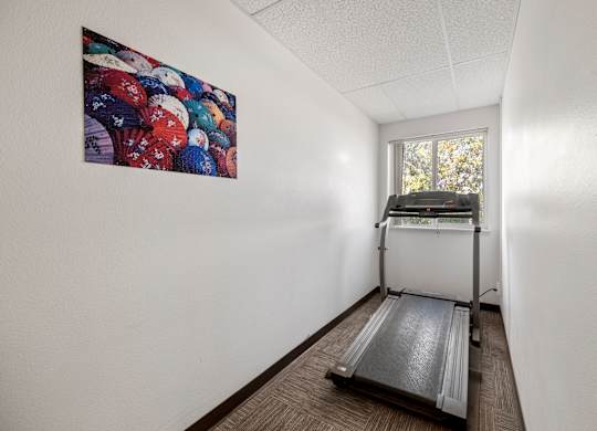 A treadmill is in a room with a painting on the wall.